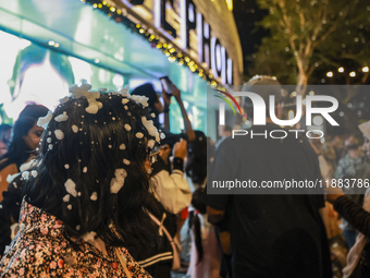 Visitors celebrate after artificial snow fills the Christmas decoration outside a shopping mall in Kuala Lumpur, Malaysia, on December 19, 2...