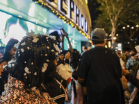 Visitors celebrate after artificial snow fills the Christmas decoration outside a shopping mall in Kuala Lumpur, Malaysia, on December 19, 2...