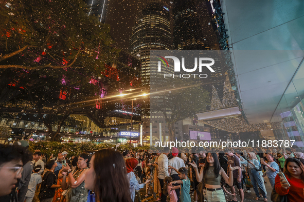 Visitors celebrate after artificial snow fills the Christmas decoration outside a shopping mall in Kuala Lumpur, Malaysia, on December 19, 2...