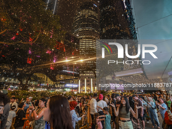 Visitors celebrate after artificial snow fills the Christmas decoration outside a shopping mall in Kuala Lumpur, Malaysia, on December 19, 2...