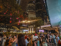 Visitors celebrate after artificial snow fills the Christmas decoration outside a shopping mall in Kuala Lumpur, Malaysia, on December 19, 2...