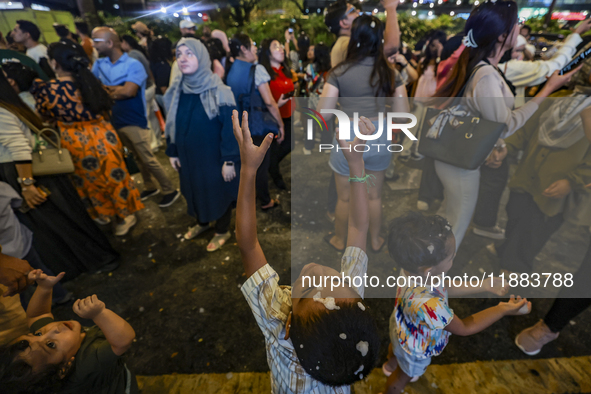 Visitors celebrate after artificial snow fills the Christmas decoration outside a shopping mall in Kuala Lumpur, Malaysia, on December 19, 2...