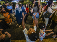 Visitors celebrate after artificial snow fills the Christmas decoration outside a shopping mall in Kuala Lumpur, Malaysia, on December 19, 2...