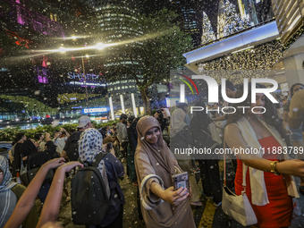 Visitors celebrate after artificial snow fills the Christmas decoration outside a shopping mall in Kuala Lumpur, Malaysia, on December 19, 2...