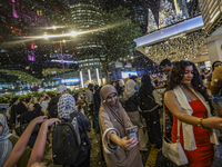 Visitors celebrate after artificial snow fills the Christmas decoration outside a shopping mall in Kuala Lumpur, Malaysia, on December 19, 2...