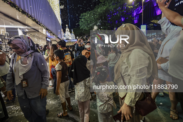 Visitors celebrate after artificial snow fills the Christmas decoration outside a shopping mall in Kuala Lumpur, Malaysia, on December 19, 2...