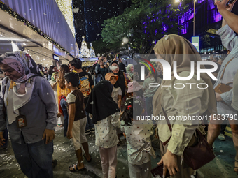 Visitors celebrate after artificial snow fills the Christmas decoration outside a shopping mall in Kuala Lumpur, Malaysia, on December 19, 2...