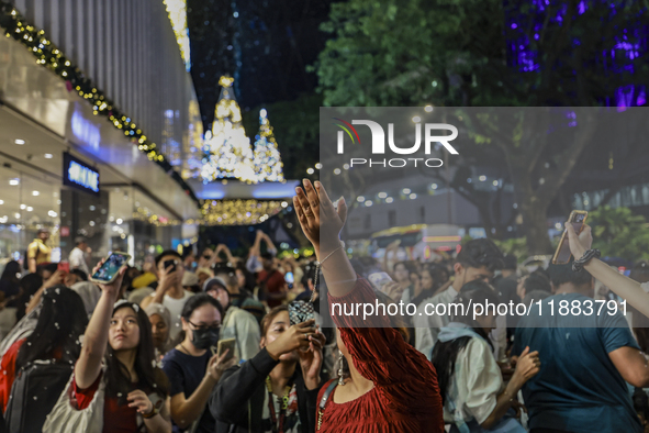 Visitors celebrate after artificial snow fills the Christmas decoration outside a shopping mall in Kuala Lumpur, Malaysia, on December 19, 2...