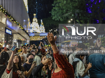 Visitors celebrate after artificial snow fills the Christmas decoration outside a shopping mall in Kuala Lumpur, Malaysia, on December 19, 2...