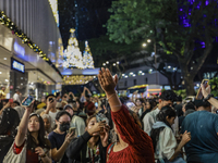 Visitors celebrate after artificial snow fills the Christmas decoration outside a shopping mall in Kuala Lumpur, Malaysia, on December 19, 2...