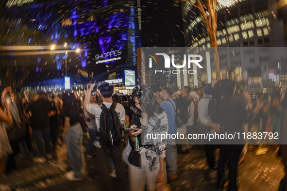 Visitors celebrate after artificial snow fills the Christmas decoration outside a shopping mall in Kuala Lumpur, Malaysia, on December 19, 2...