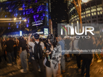 Visitors celebrate after artificial snow fills the Christmas decoration outside a shopping mall in Kuala Lumpur, Malaysia, on December 19, 2...