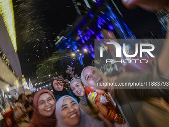 Visitors celebrate after artificial snow fills the Christmas decoration outside a shopping mall in Kuala Lumpur, Malaysia, on December 19, 2...