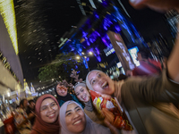 Visitors celebrate after artificial snow fills the Christmas decoration outside a shopping mall in Kuala Lumpur, Malaysia, on December 19, 2...