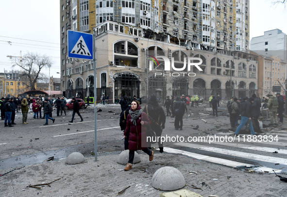 A woman crosses the street near a building in the Holosiivskyi district damaged by a Russian missile attack in Kyiv, Ukraine, on December 20...