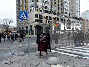 A woman crosses the street near a building in the Holosiivskyi district damaged by a Russian missile attack in Kyiv, Ukraine, on December 20...