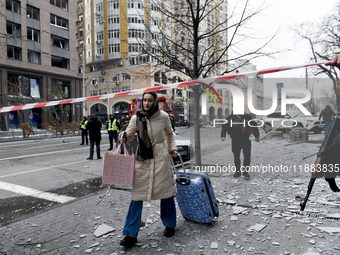 A woman pulls a suitcase along the street in the Holosiivskyi district covered with debris after a Russian missile attack in Kyiv, Ukraine,...