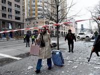 A woman pulls a suitcase along the street in the Holosiivskyi district covered with debris after a Russian missile attack in Kyiv, Ukraine,...