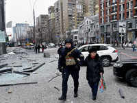 A police officer escorts an elderly woman in the street in the Holosiivskyi district damaged by a Russian missile attack in Kyiv, Ukraine, o...