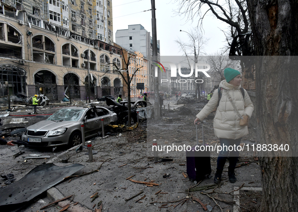 A woman with a suitcase stands in the street in the Holosiivskyi district damaged by a Russian missile attack in Kyiv, Ukraine, on December...