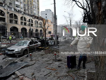 A woman with a suitcase stands in the street in the Holosiivskyi district damaged by a Russian missile attack in Kyiv, Ukraine, on December...