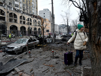 A woman with a suitcase stands in the street in the Holosiivskyi district damaged by a Russian missile attack in Kyiv, Ukraine, on December...