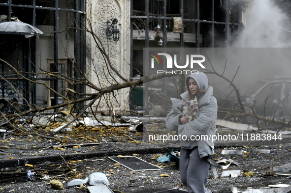 A woman carries a dog along a street covered with debris in the Holosiivskyi district after a Russian missile attack in Kyiv, Ukraine, on De...