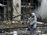 A woman carries a dog along a street covered with debris in the Holosiivskyi district after a Russian missile attack in Kyiv, Ukraine, on De...