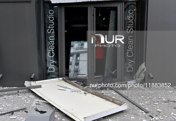 A woman stands at the smashed glass door of a dry cleaner in the Holosiivskyi district, damaged by a Russian missile attack, in Kyiv, Ukrain...