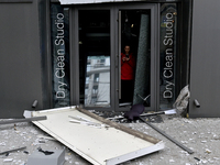 A woman stands at the smashed glass door of a dry cleaner in the Holosiivskyi district, damaged by a Russian missile attack, in Kyiv, Ukrain...