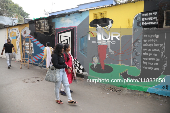 Women walk past a mural inside an alley during an open-air art festival, The Behala Art Fest, in Kolkata, India, on December 20, 2024. 