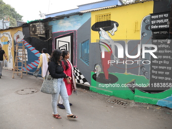 Women walk past a mural inside an alley during an open-air art festival, The Behala Art Fest, in Kolkata, India, on December 20, 2024. (