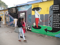 Women walk past a mural inside an alley during an open-air art festival, The Behala Art Fest, in Kolkata, India, on December 20, 2024. (