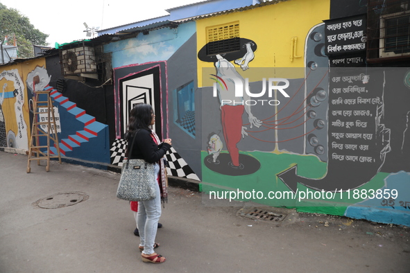 People walk past a mural inside an alley during an open-air art festival, The Behala Art Fest, in Kolkata, India, on December 20, 2024. 