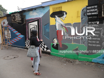 People walk past a mural inside an alley during an open-air art festival, The Behala Art Fest, in Kolkata, India, on December 20, 2024. (