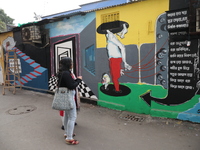 People walk past a mural inside an alley during an open-air art festival, The Behala Art Fest, in Kolkata, India, on December 20, 2024. (