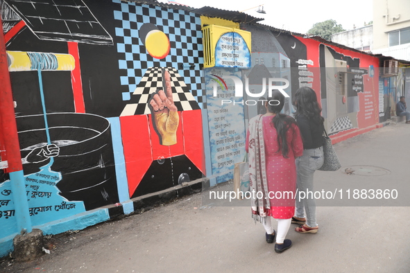 Women walk past a mural inside an alley during an open-air art festival, The Behala Art Fest, in Kolkata, India, on December 20, 2024. 