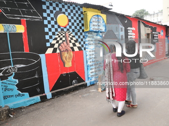 Women walk past a mural inside an alley during an open-air art festival, The Behala Art Fest, in Kolkata, India, on December 20, 2024. (