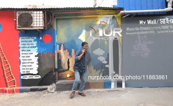 A man speaks on his mobile phone in front of a mural inside an alley during an open-air art festival, The Behala Art Fest, in Kolkata, India...