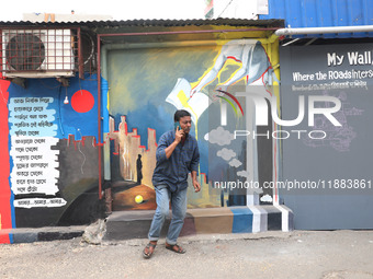 A man speaks on his mobile phone in front of a mural inside an alley during an open-air art festival, The Behala Art Fest, in Kolkata, India...