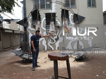 A man holds an art installation inside an alley during an open-air art festival, The Behala Art Fest, in Kolkata, India, on December 20, 202...