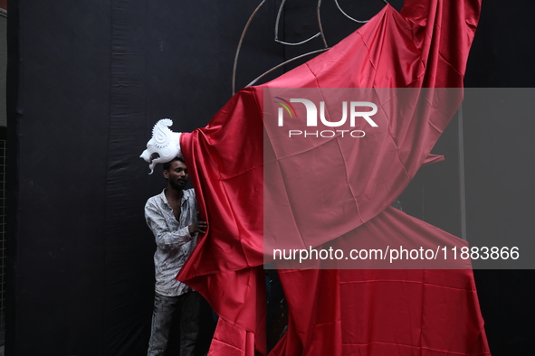 An artist works on a sculpture installed inside an alley during the open-air art festival, The Behala Art Fest, in Kolkata, India, on Decemb...