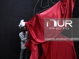 An artist works on a sculpture installed inside an alley during the open-air art festival, The Behala Art Fest, in Kolkata, India, on Decemb...