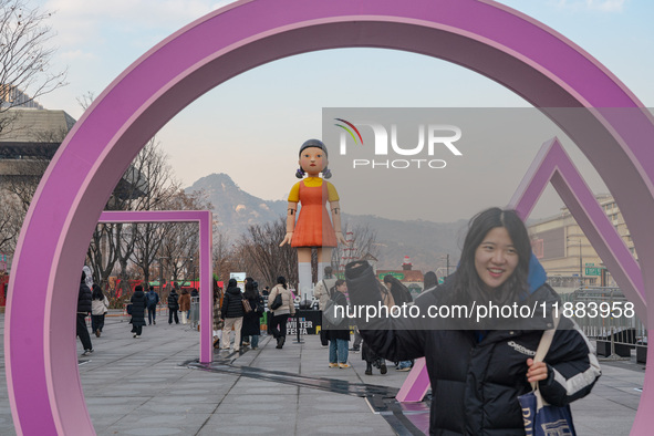 People take photos in front of Young-hee, a robotic doll from Netflix's ''Squid Game,'' at Gwanghwamun Square in Seoul, South Korea, on Dece...