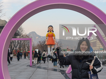 People take photos in front of Young-hee, a robotic doll from Netflix's ''Squid Game,'' at Gwanghwamun Square in Seoul, South Korea, on Dece...