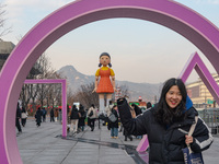 People take photos in front of Young-hee, a robotic doll from Netflix's ''Squid Game,'' at Gwanghwamun Square in Seoul, South Korea, on Dece...