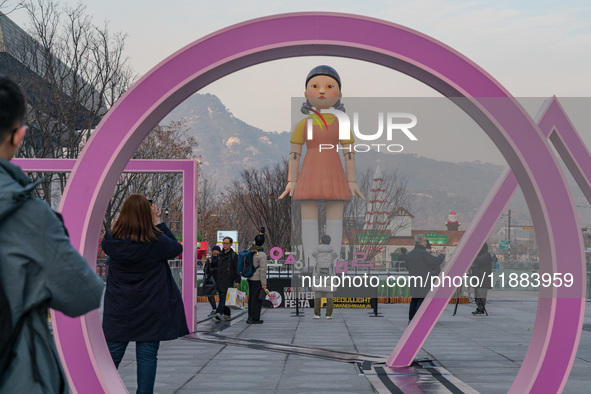 People take photos in front of Young-hee, a robotic doll from Netflix's ''Squid Game,'' at Gwanghwamun Square in Seoul, South Korea, on Dece...