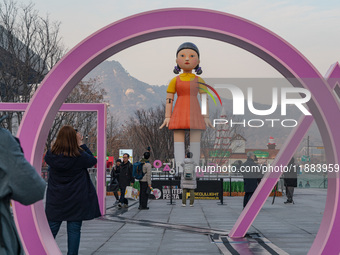 People take photos in front of Young-hee, a robotic doll from Netflix's ''Squid Game,'' at Gwanghwamun Square in Seoul, South Korea, on Dece...