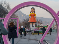 People take photos in front of Young-hee, a robotic doll from Netflix's ''Squid Game,'' at Gwanghwamun Square in Seoul, South Korea, on Dece...