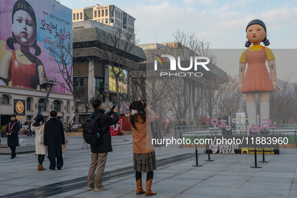 People take photos in front of Young-hee, a robotic doll from Netflix's ''Squid Game,'' at Gwanghwamun Square in Seoul, South Korea, on Dece...